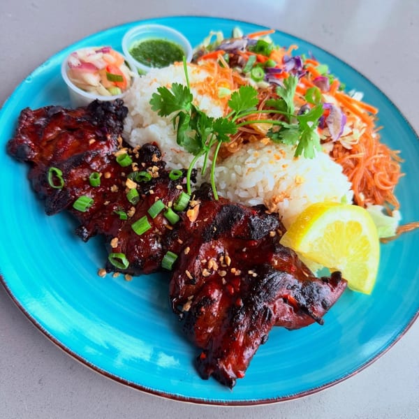 CheBogz Filipino dish with grilled chicken, rice, noodles, and a side salad on a blue plate.