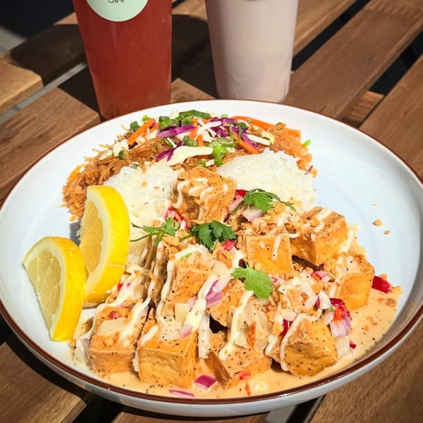 Filipino dish with fried tofu, rice, noodles, vegetables, and lemon wedges on a white plate.