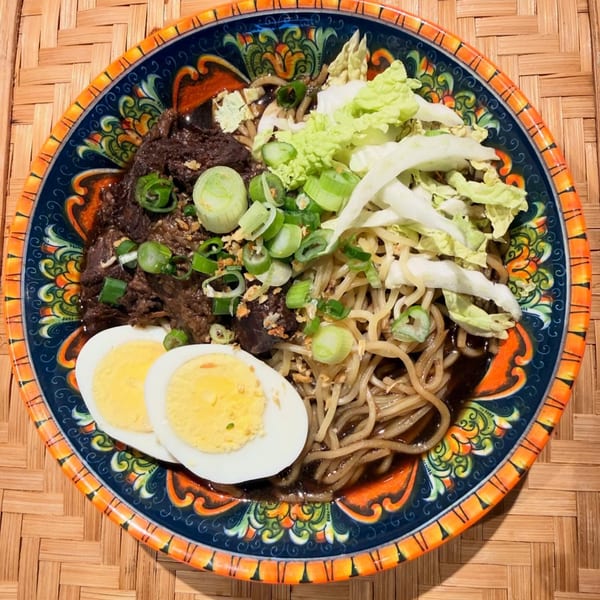 CheBogz Filipino Pancit Palabok with noodles, beef, cabbage, green onions, and hard-boiled eggs.