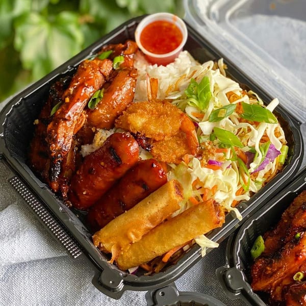A CheBogz Filipino takeout container filled with rice, lumpia, sausages, shrimp, and vegetables.